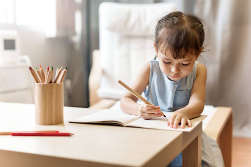 a toddler writing on a wooden table and chair set