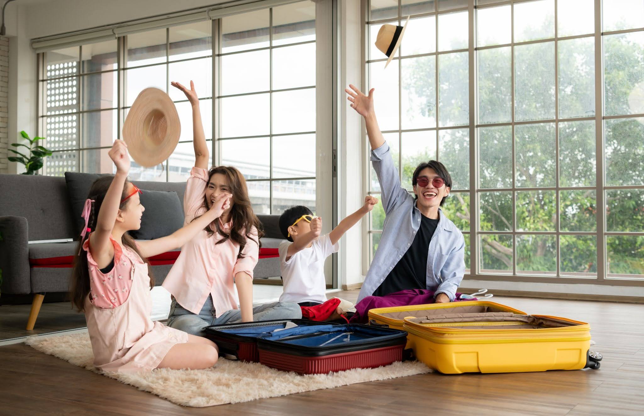 Cheerful family packing open luggage on the living room floor for a trip